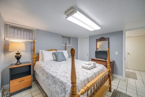Ein Schlafzimmer mit einem Bett, Nachttischen, einer Lampe, einem Spiegel und einem Fernseher.
