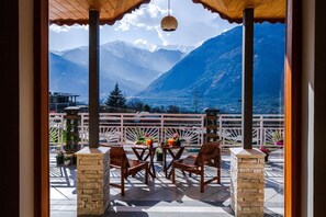 Una terraza con vistas a las montañas, una mesa con sillas y una lámpara colgante.