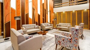 A spacious living area with sofas and armchairs, a coffee table, and a floor lamp. - Anand Vardhan Resorts (Kullu)