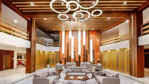 A spacious lobby with a central seating area, wooden ceiling beams, and a modern chandelier. - Anand Vardhan Resorts (Kullu)