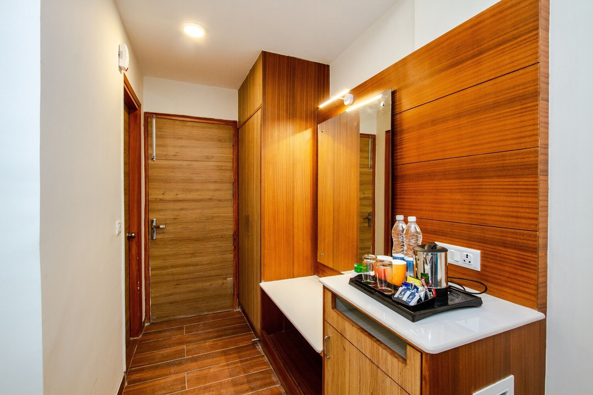 A modern bathroom with wooden cabinetry, a countertop with toiletries, and a mirror.