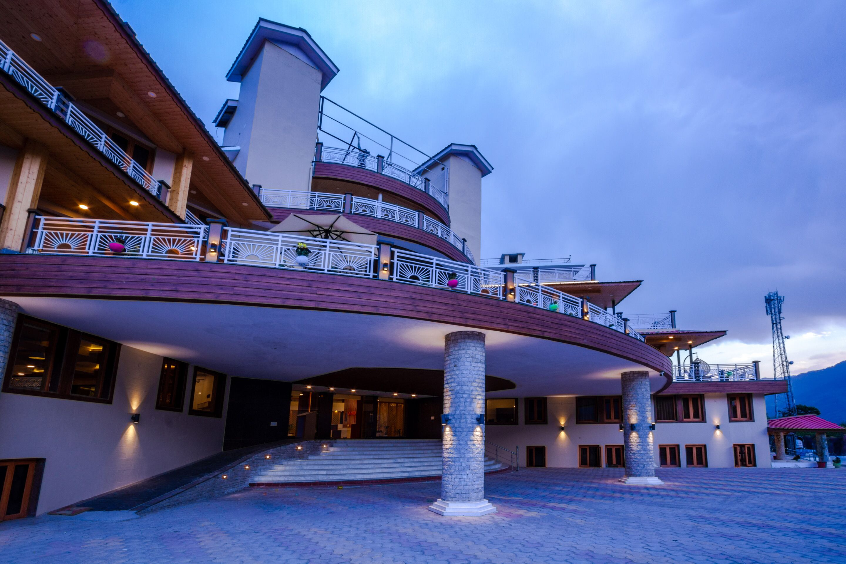 Un hotel con fachada curva, varios balcones y un patio central.