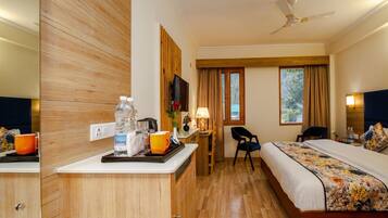 Une chambre d’hôtel avec un meuble en bois, un lit recouvert d’une courtepointe à motifs floraux, un bureau avec une lampe et une fenêtre avec des rideaux.