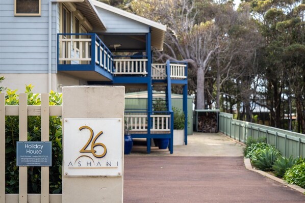 Escape to Holiday House 26, where a balcony and staircase lead to a serene upper level amidst lush surroundings.