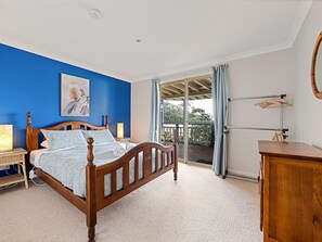 Cozy retreat with a large bed, wooden dresser, and a window offering a view of the outdoors.