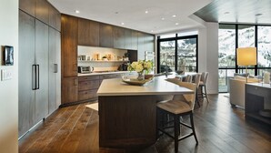 Una cocina moderna con una isla grande, armarios de madera y vista a un paisaje nevado.