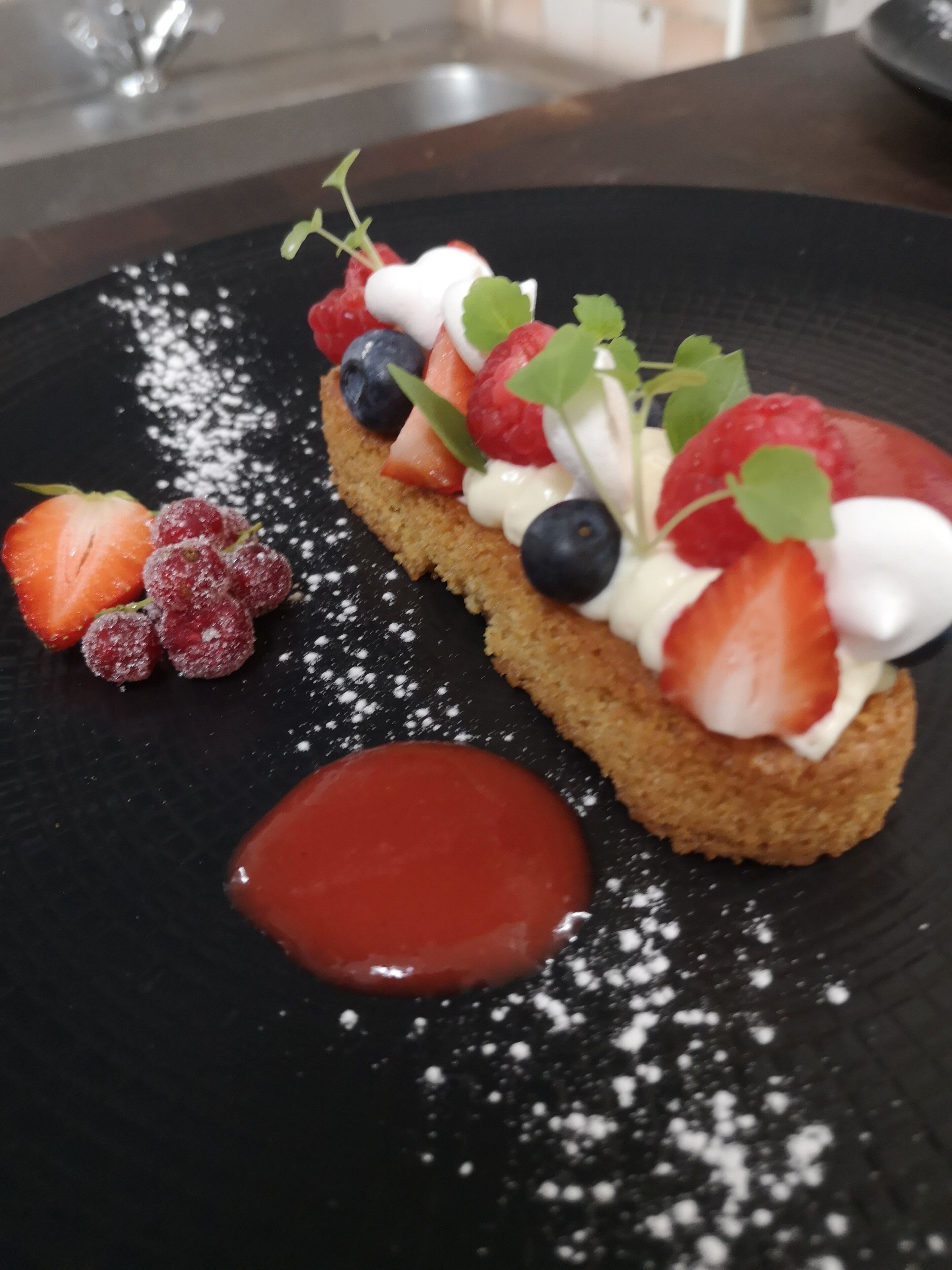 Postre con fresas, arándanos, frambuesas y crema en un plato.