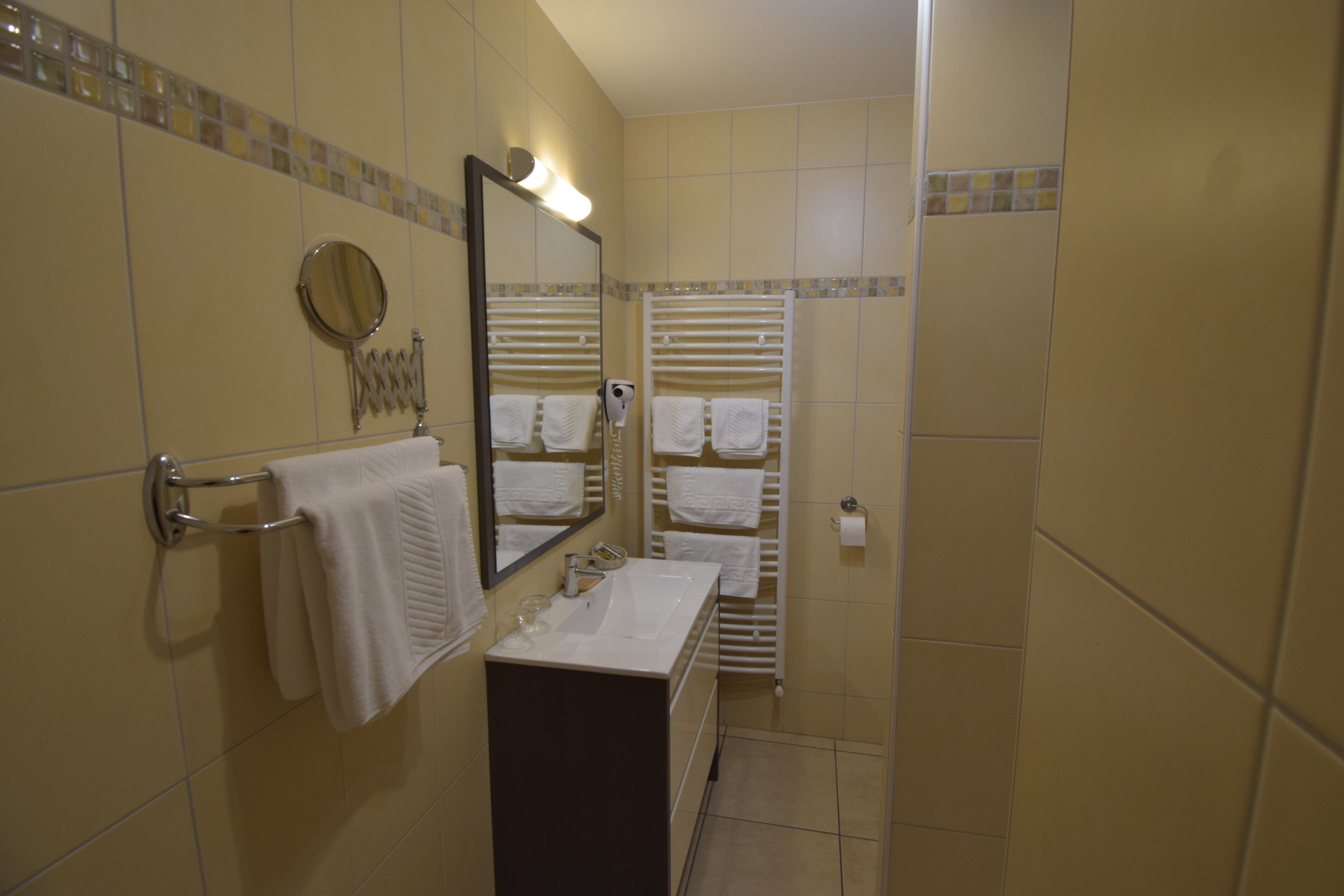 A bathroom with a sink, mirror, towel rack, and a heated towel rail.
