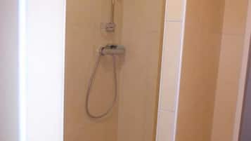 A small, enclosed shower area with a handheld showerhead and a floor drain.