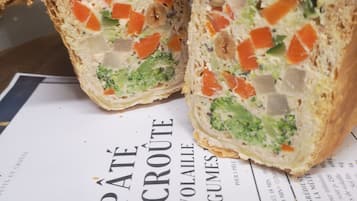 Ein halbierter Sandwich mit sichtbaren Zutaten wie Gemüse und Fleisch, platziert auf einer Speisekarte mit der Aufschrift 'P'tit Croûte'.