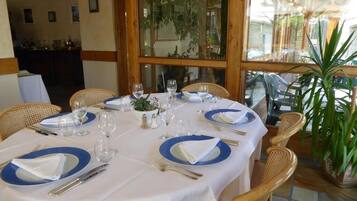 Une table à manger dressée pour quatre personnes, avec de l’argenterie, des assiettes bleues et blanches et des verres à vin.