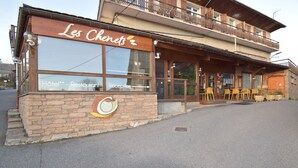 Un hotel con un letrero que dice "Les Chenets" y un área de recepción con sillas amarillas en el exterior.