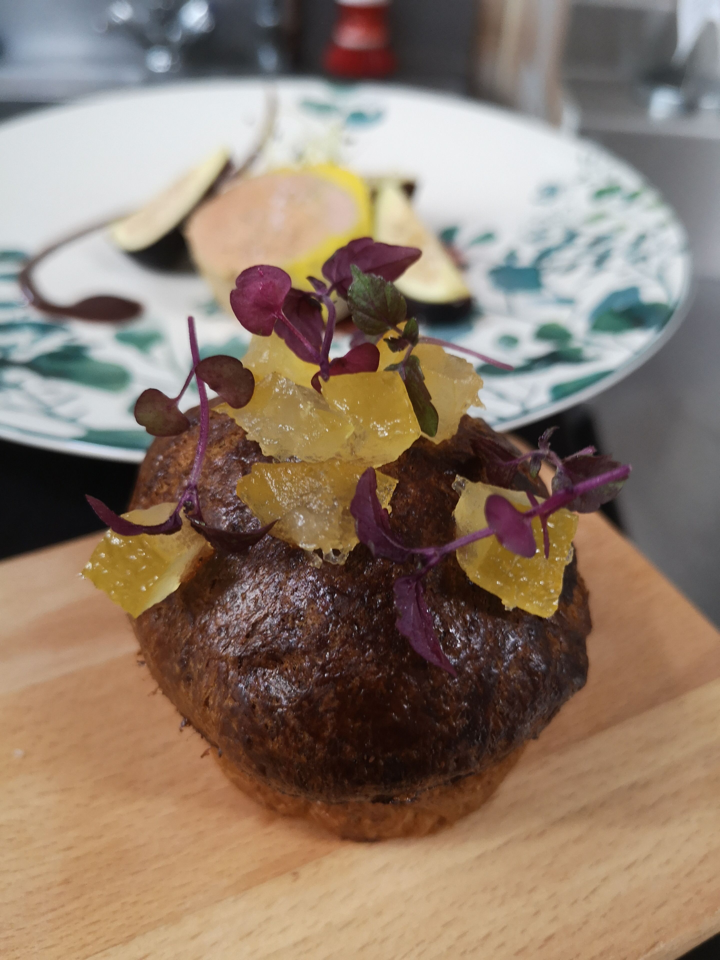 Un muffin garni de fruits et de légumes verts, présenté sur une planche en bois.