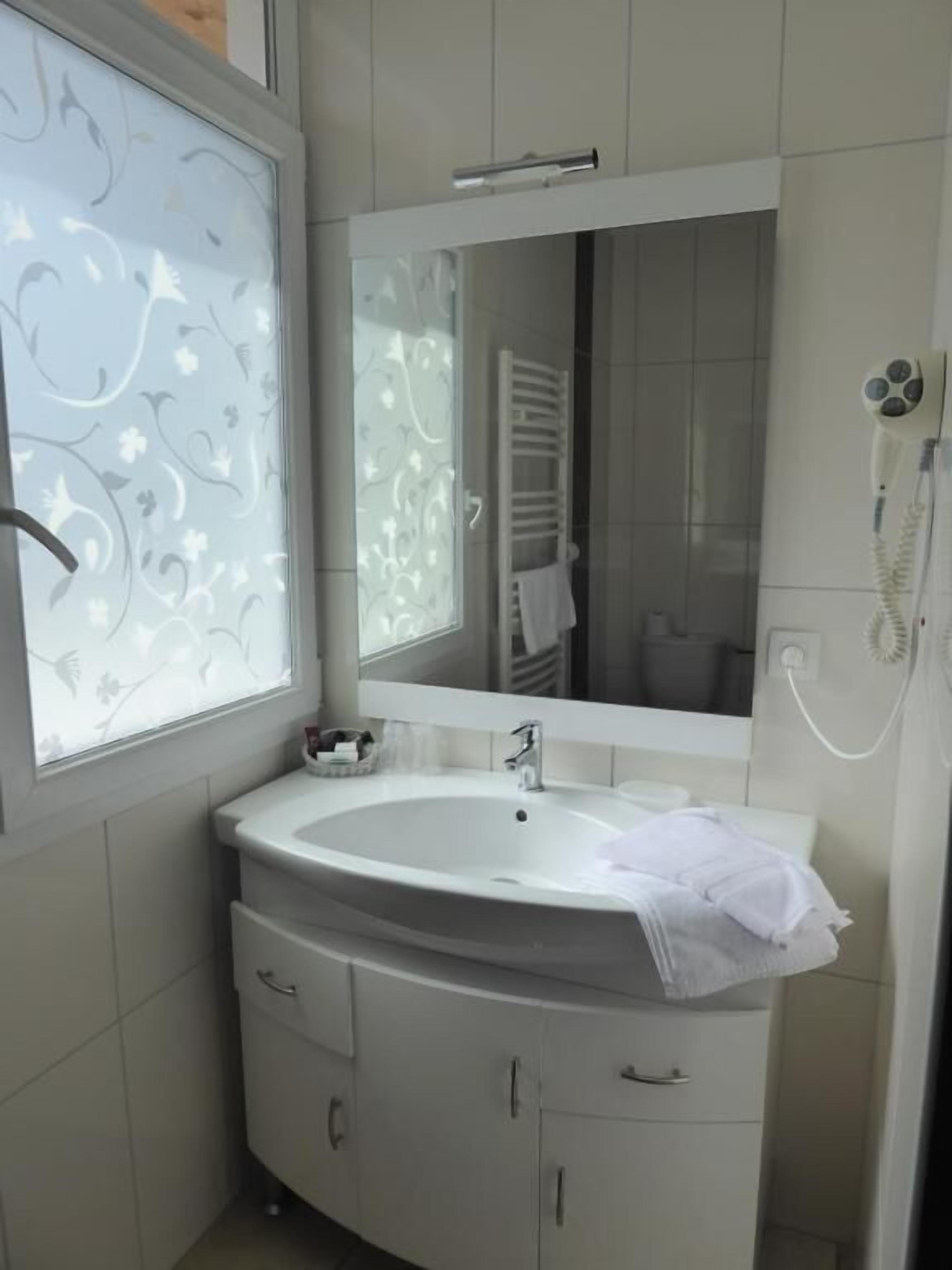 A bathroom with a white sink, a mirror, and a towel rack.