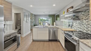 A modern kitchen with a dishwasher, oven, and granite countertops. - Carolina Sunrise by SoCharm | Amazing Sunrises | Hot tub (Denver)