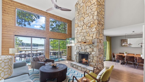 A spacious living area with a stone fireplace, large windows, and a view of the outdoors. - Carolina Sunrise by SoCharm | Amazing Sunrises | Hot tub (Denver)