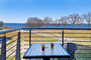 Een balkon met een tafel en stoelen, met uitzicht op water en bomen.
