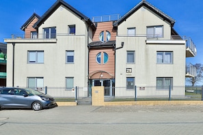 Un immeuble de deux étages avec une entrée centrale, portant le numéro 29, et une voiture garée devant.