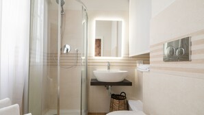 A modern bathroom with a glass shower enclosure, a white sink, and a toilet.