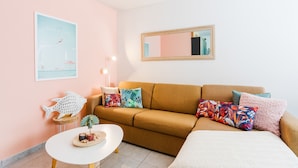 A cozy living room with a brown sofa, colorful pillows, a small table with a plant, and a framed picture on the wall. - PALAIS LIBERTE V AP4267 By Riviera Holiday Homes (Niza)