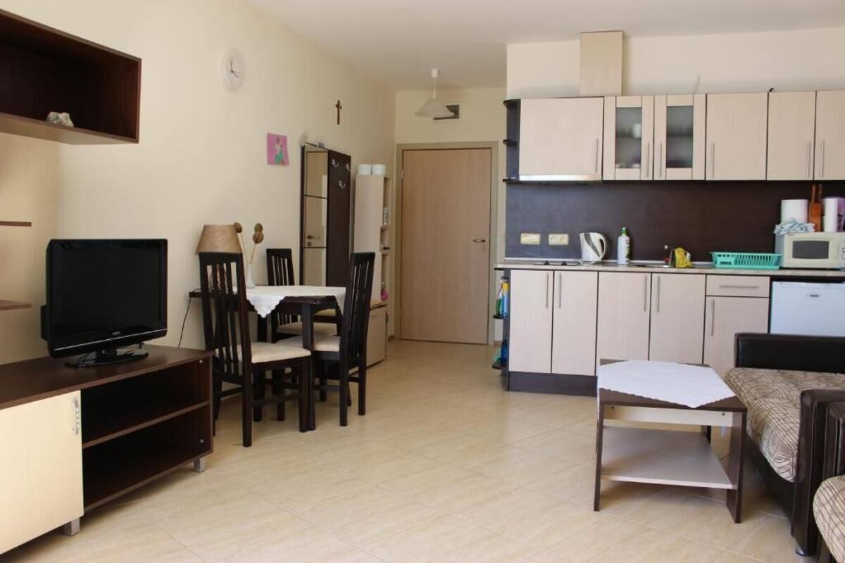 Un espacio habitable compacto con zona de comedor, kitchenette y televisor.