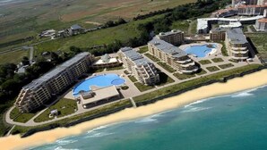 A coastal hotel with multiple buildings, a beach, and a large swimming pool. - Aheloy Palace Apartments (Pomorie)