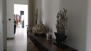 A hallway with a wooden console table, a glass container, and decorative branches. - Villa Moderne 5 Min Mer - Piscine Idéale Familles, Proche Station de Ski 🏖️❄️ (Ventiseri)