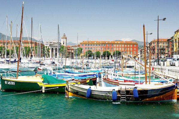 Un port de plaisance où sont amarrés différents types de bateaux, une tour de l’horloge et des bâtiments en arrière-plan.