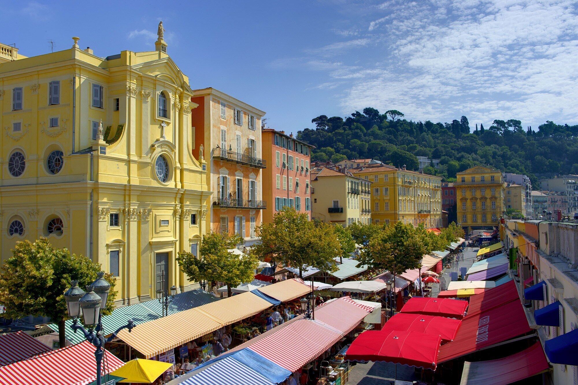 A street lined with colorful buildings and outdoor market stalls.