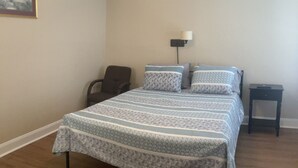 Une chambre à coucher avec un grand lit, une chaise, une table de chevet et une lampe fixée au mur.