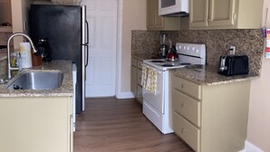 Une cuisine compacte équipée d’un réfrigérateur, d’un four à micro-ondes, d’une cuisinière et d’un grille-pain.