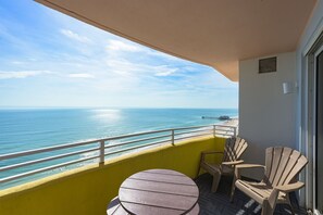 Relax on the balcony with a round table and two Adirondack chairs, taking in the ocean view and pier in the distance.