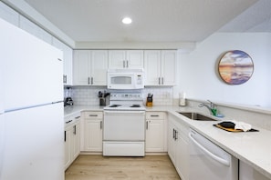 Modern kitchen with appliances, including a microwave, stove, and dishwasher, and a spacious countertop with a sink and knife block.
