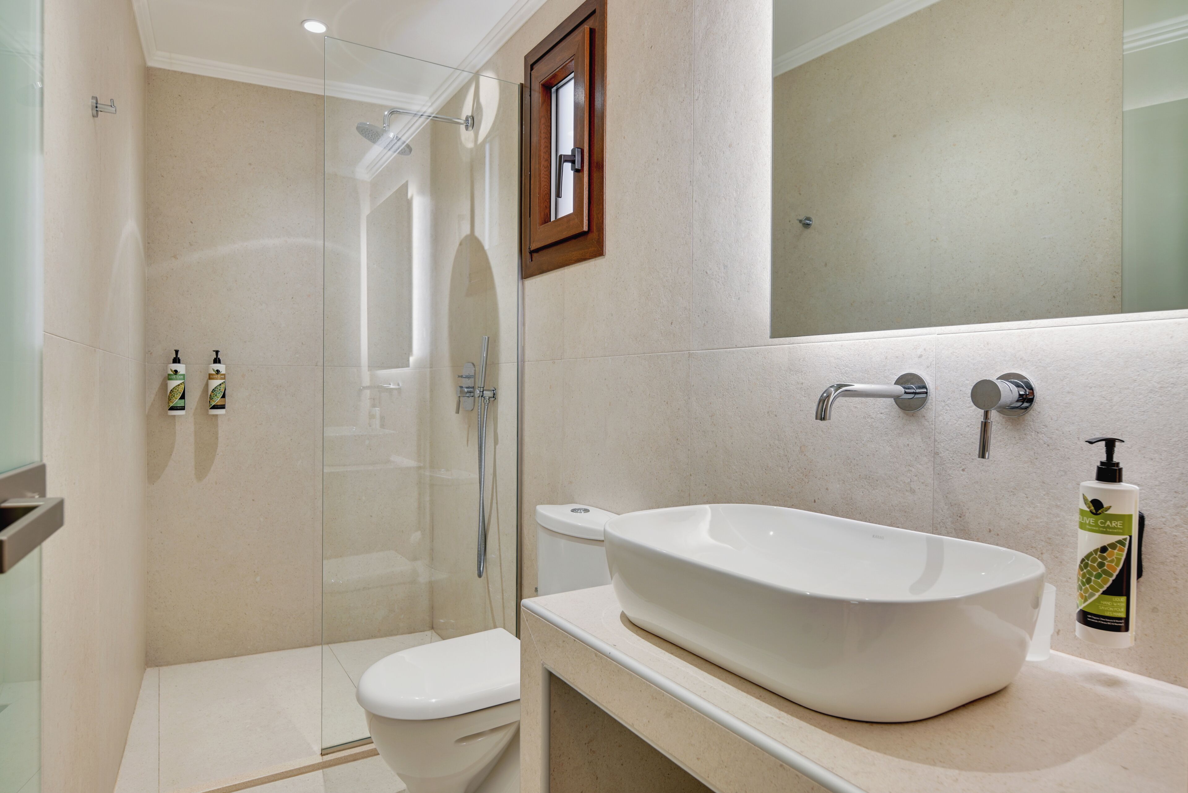 Un baño moderno con ducha de vidrio, lavamanos blanco y retrete.