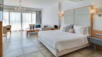 Ett modernt hotellrum med en stor säng, ett skrivbord, en stol, en kristallkrona och ett stort fönster med gardiner.