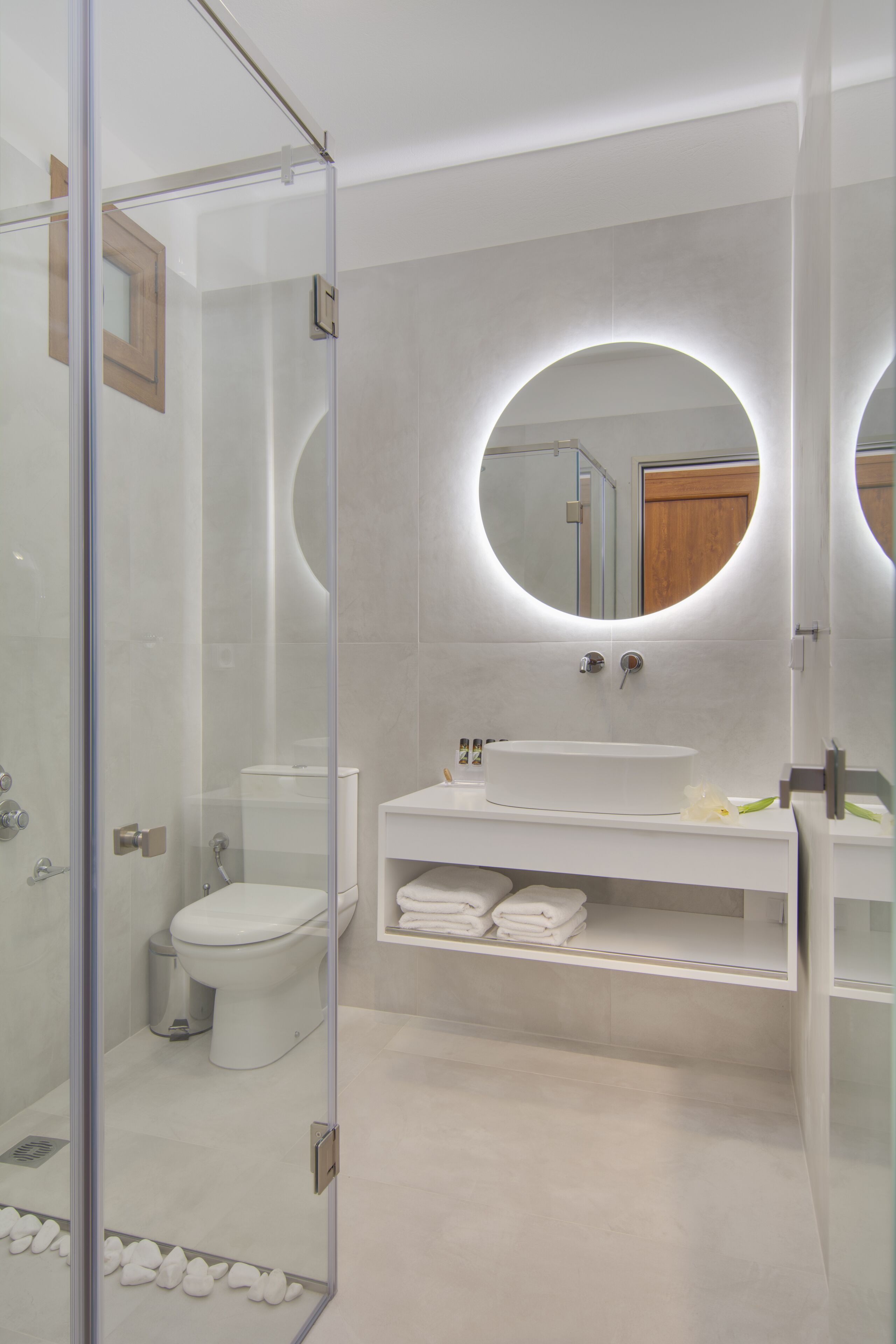 A modern bathroom with a glass-enclosed shower, a white sink, and a toilet.