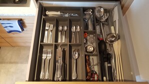 Un tiroir contenant divers ustensiles de cuisine et couverts, notamment des fourchettes, des couteaux, des cuillères et une râpe.