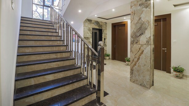 Un moderno vestíbulo de hotel con una escalera de mármol, una mesa de recepción y una gran columna de mármol.