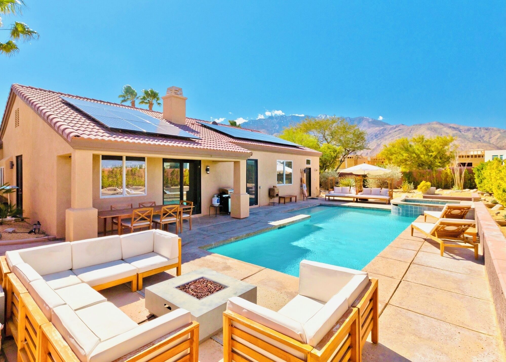 A modern house with a swimming pool, outdoor seating, and a mountain view.