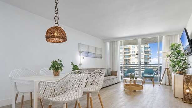 Ein modernes Wohnzimmer mit Essbereich, großen Fenstern und Blick auf hohe Gebäude.