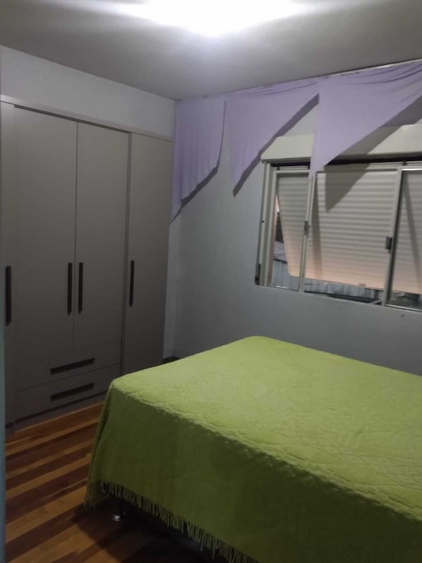 A bedroom with a bed, wardrobe, and window.