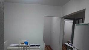A compact kitchen with a dining table, chairs, a refrigerator, and a wooden floor.