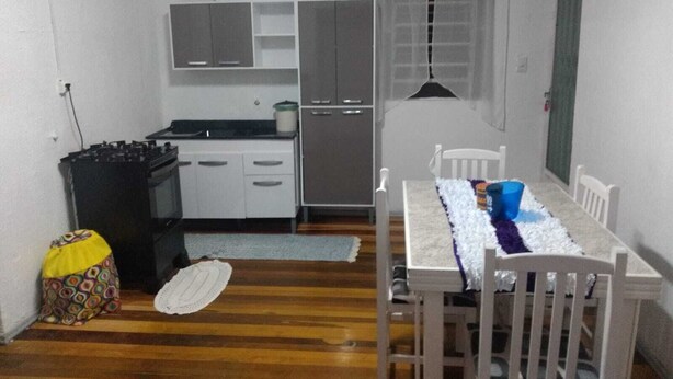 A compact kitchen with white cabinets, a refrigerator, and a dining table with chairs.