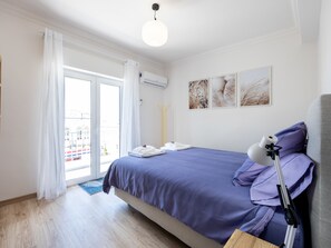 Un dormitorio moderno con una cama grande, un escritorio con lámpara y vistas a través de un ventanal corredero.