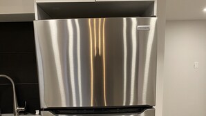 Ein Edelstahl-Kühlschrank in einer Küche mit weißen Schränken und einer schwarzen Spritzschutzwand.