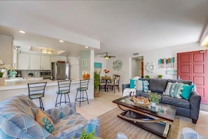 A modern living room with a sofa, coffee table, and a dining area with chairs.