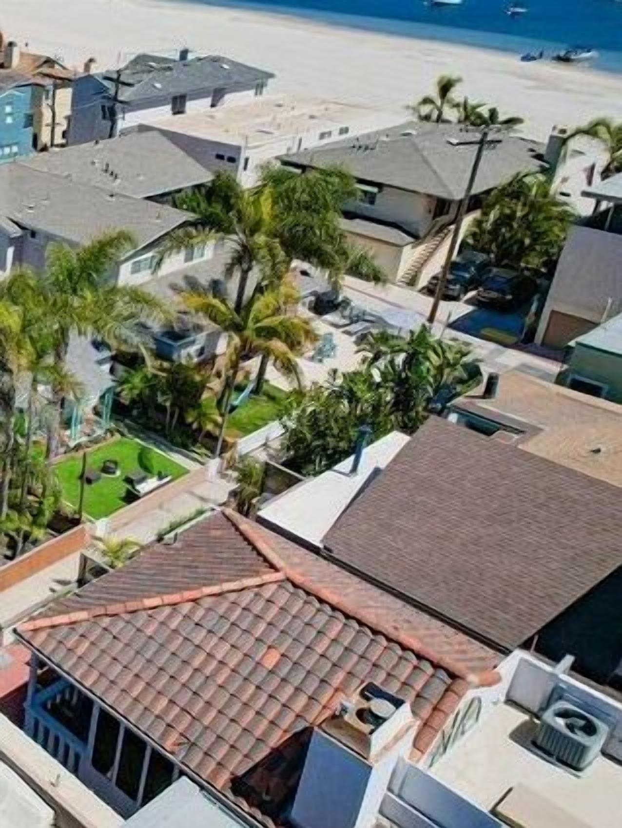 Une zone résidentielle côtière, avec des maisons, dont certaines sont coiffées de toits en tuiles, et des palmiers.