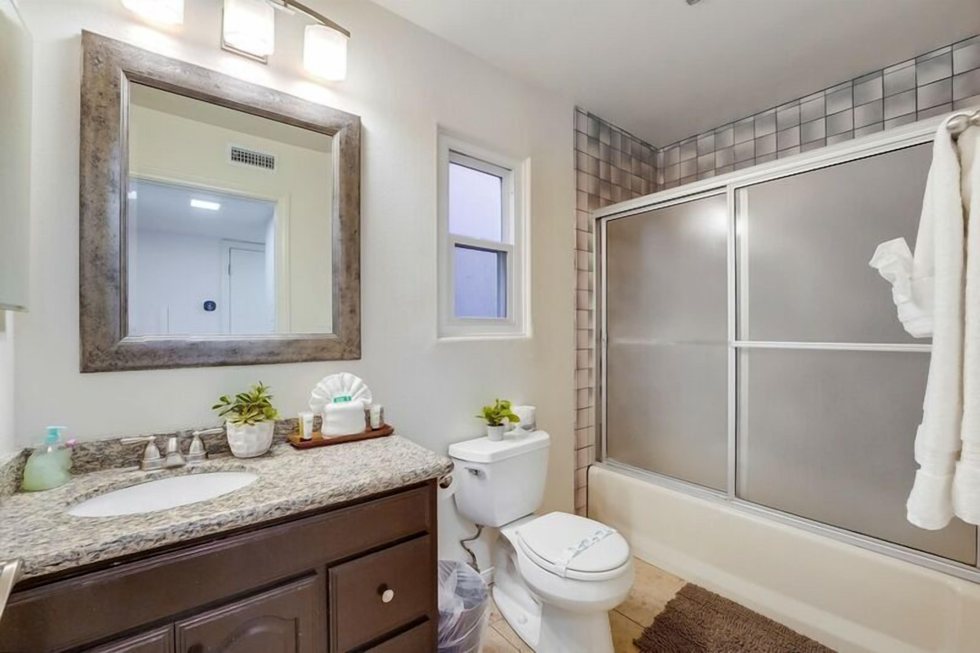 Une salle de bain avec un grand miroir, deux lavabos, des toilettes et une douche.