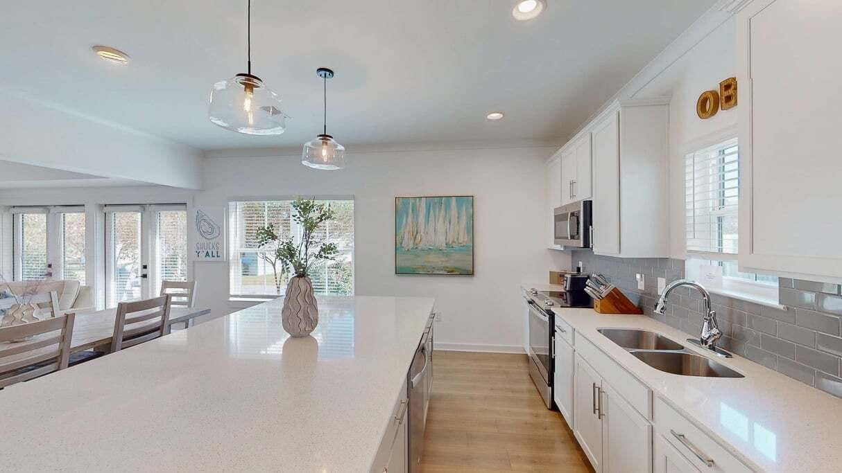 A modern kitchen with white cabinetry, a large island, and pendant lighting.