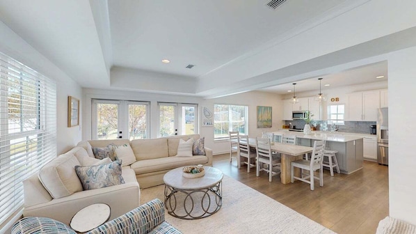 A spacious living area with a sofa, coffee table, and dining set. - Pet-friendly Oasis w/Pool & Kayak Slip near Beach (Orange Beach)